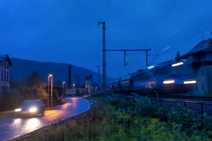 Güterzug und PKW bei Nacht nebeneinander