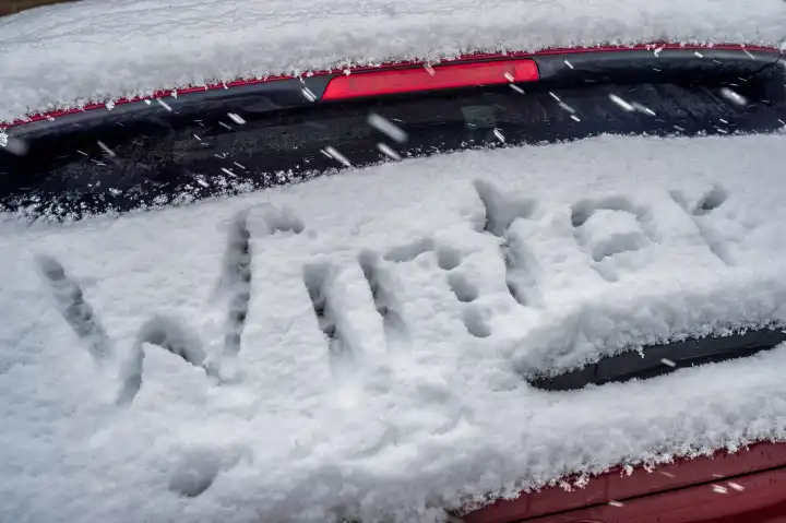 Schriftzug "Winter" auf eingeschneiter Heckscheibe eines PKW