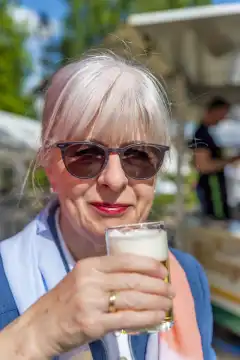Ältere Frau mit Sonnenbrille und Bierglas, Kamerablick, aufrecht, Deutschland, Nordrhein-Westfalen, Grevenbroich, öffentlicher Platz