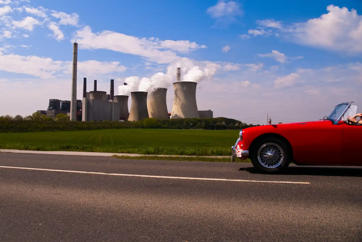 a classic car drives past the power plant