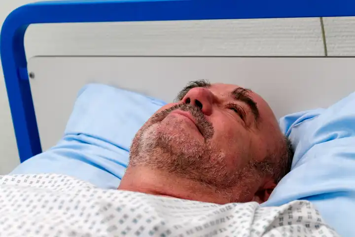 Mann liegt in einem Krankenhausbett