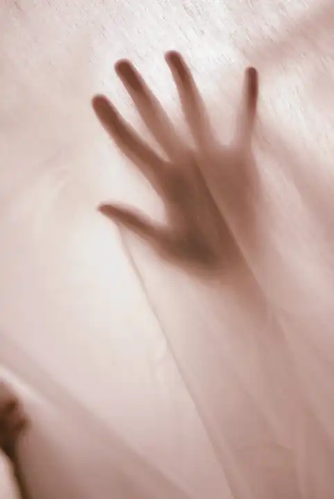 woman's hand behind curtain