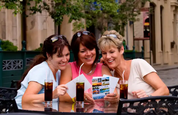 Tourist girl friends relax with drinks and look at postcards and have fun in Old Havana in Habana Cuba