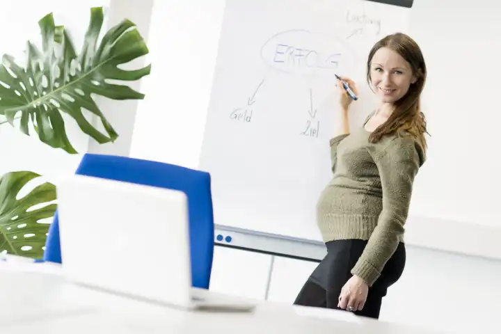 Schwangere Frau mit Flip Chart im Büro