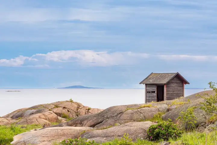 Baltic Sea coast with rocks and wooden hut near Oskashamn in Sweden.