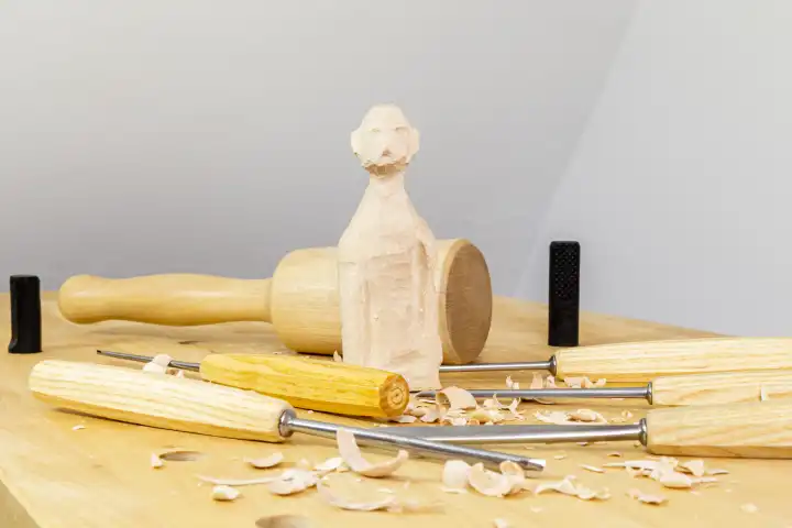 sculpting work bench with chisel, gouge, wooden mallet and figure from wood