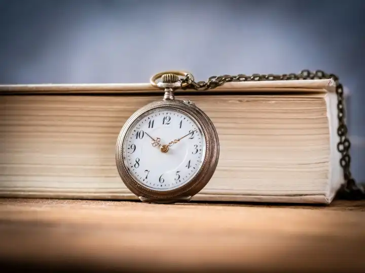Old chain clock in front of a book