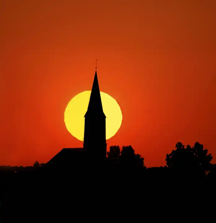 sunset behind church tower silhoutte in the eifel