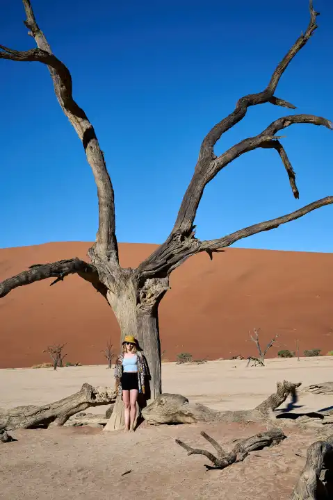 Young woman in front of an old tree in Deadvlei, Namibia