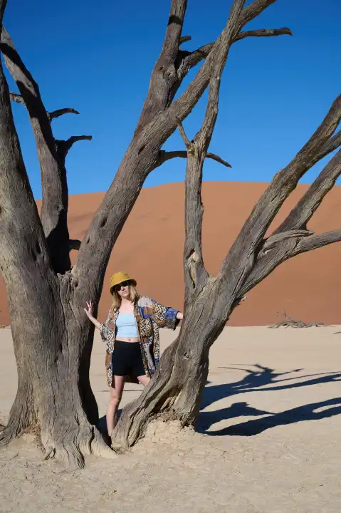Junge Frau vor altem Baum in der Wüste