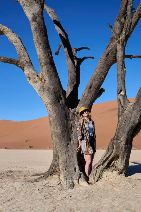 Young woman in front of an old tree in Deadvlei, Namibia