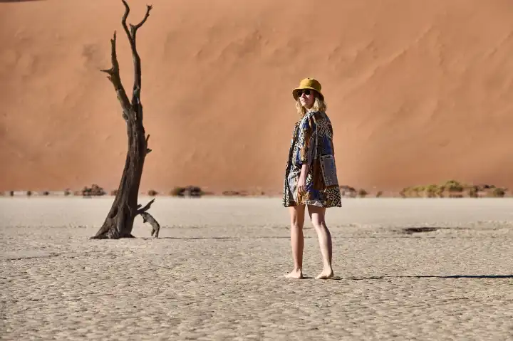 Young woman in front of dune and old tree in Deadvlei, Namibia