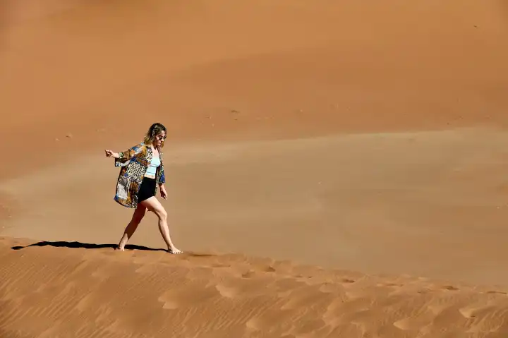 Young woman runs through sandy desert in Namibia