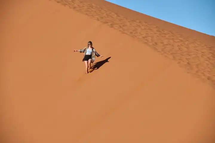 Junge Frau lauft eine Sanddüne hinunter