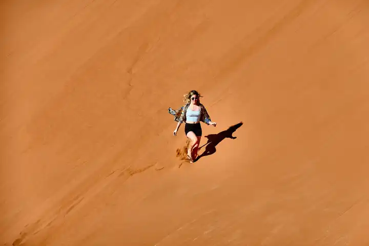 Young woman walking down a sand dune