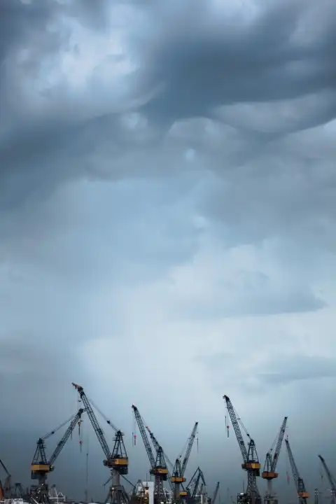 Extinguisher cranes at the Port of Hamburg under threatening sky