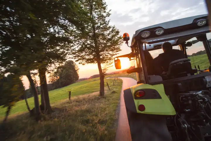 Traktor auf Feldweg bei Sonnenuntergang