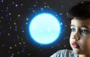 Child looks into a luminous sphere, stars reflected in his eyes, generated with AI