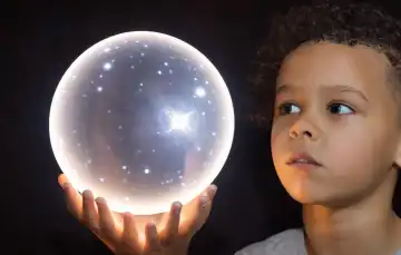 Child looks into a luminous sphere, stars reflected in his eyes, generated with AI