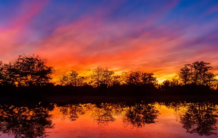 Die feurigen Farben eines Sonnenuntergangs mit spiegelungen im Wasser,  KI Generative Illustration.