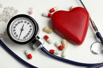 Red heart made of stone, vitamins, stethoscope, pressure gauge on white background on the table, generated with AI