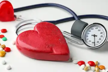 Red heart made of stone, vitamins, stethoscope, pressure gauge on white background on the table, generated with AI