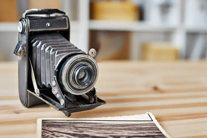 Nahaufnahme Bild der alten Vintage staubigen Kamera mit altem Bild auf unscharfen Hintergrund, selektiver Fokus. Holztisch, drinnen,  KI generiert