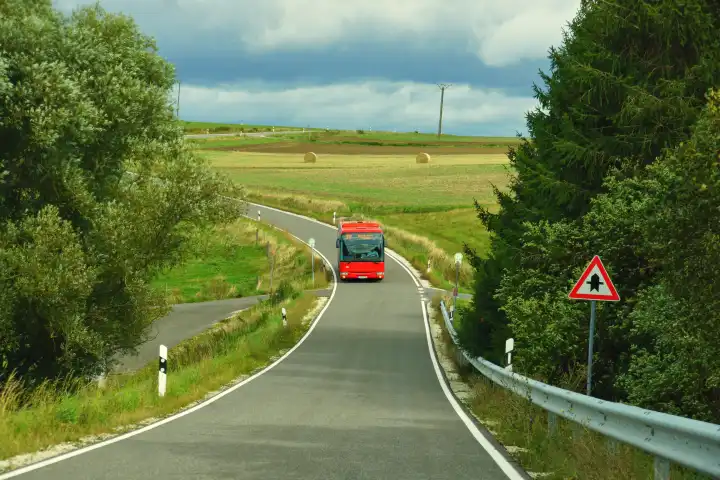 red bus in autumn on a country road in the Hunsrück