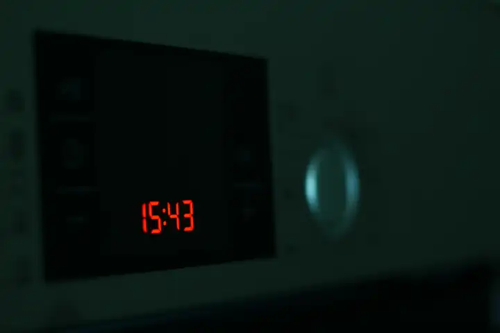 Red electronic clock on the stove in darkness