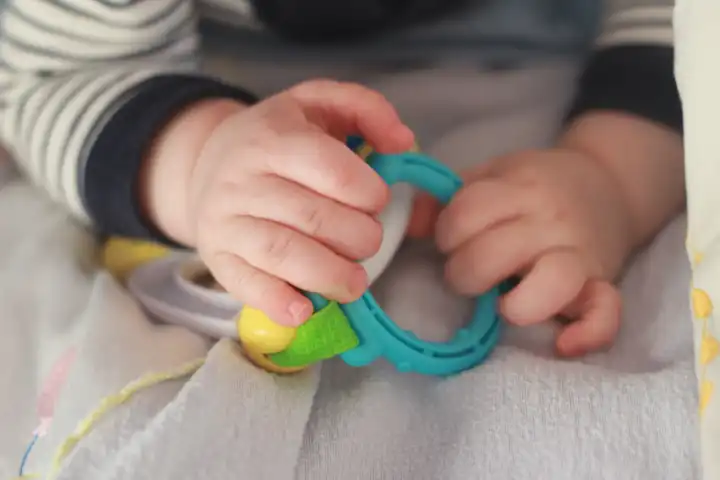 Kleines baby in einem babybett das mit spielzeug palyin