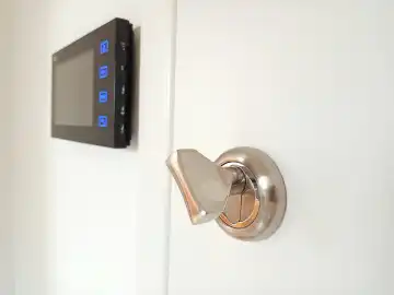 Security key in a lock and LCD camera monitoring screen on a wall