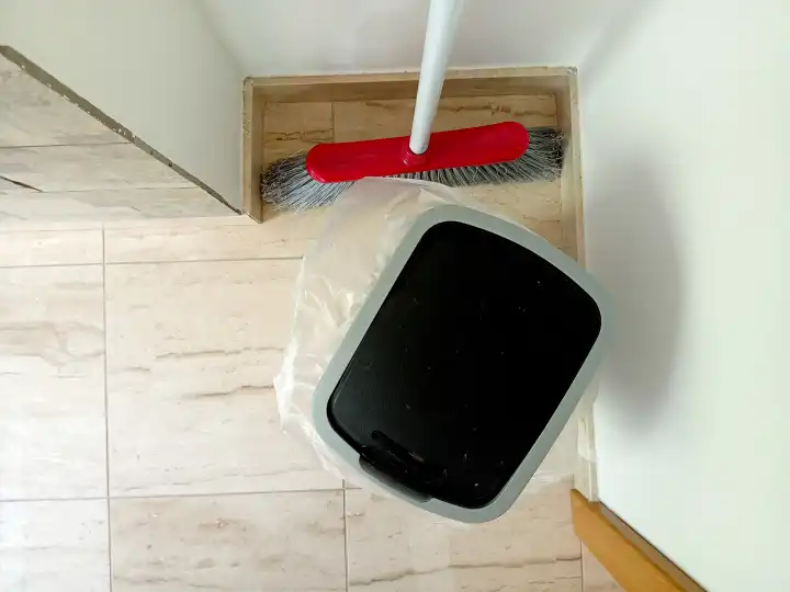 Trash bin and sweeper on floor in a room