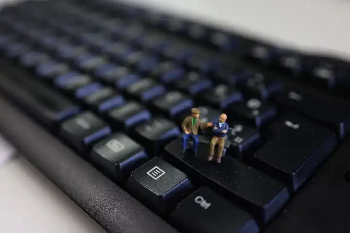 Miniature senior people on a bench on a keyboard.