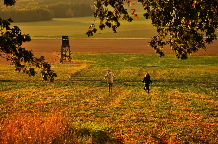 Kinder rennen über ein Feld im Herbst