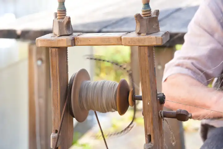 Arbeit mit altem Holzspinnrad mit Spule und Flügelarmen - Spindelspinnrad Nahaufnahme