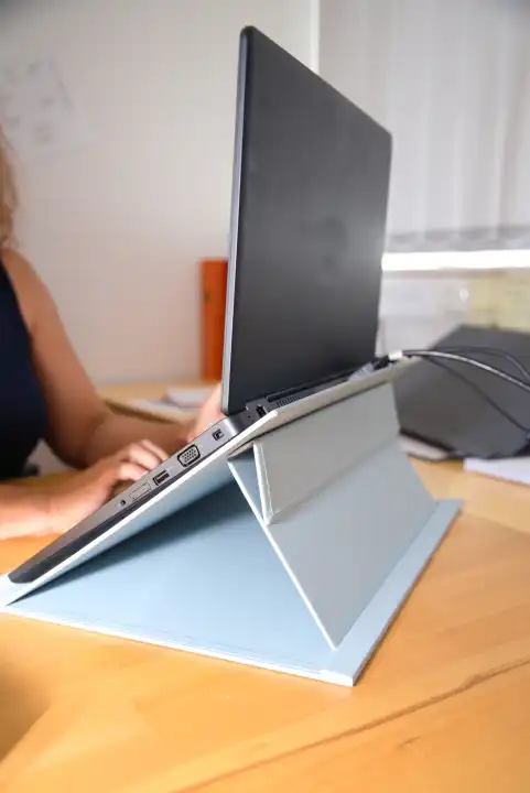 Büroangestellte arbeitet am Laptop mit Haltevorrichtung - ergonomischer Arbeitsplatz