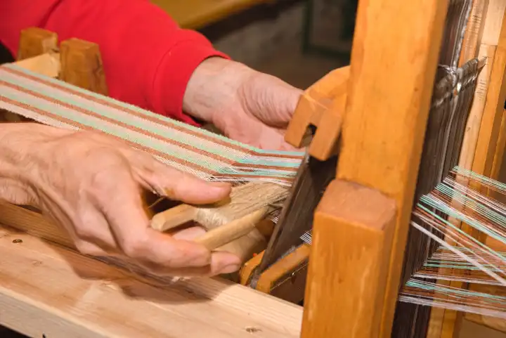 Person weaving fabric with wooden table loom