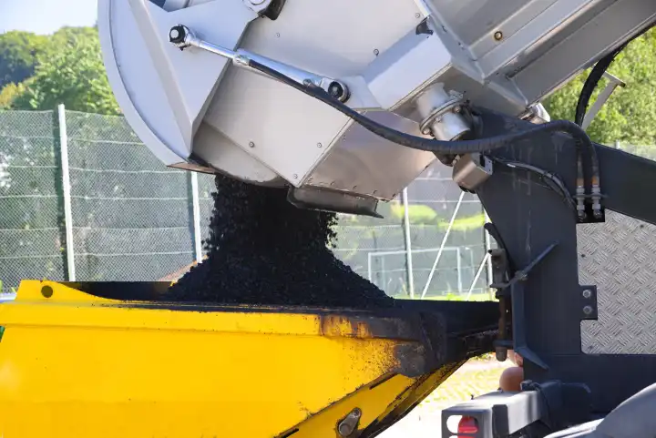 Asphalting with construction machinery - truck pours asphalt into dump truck