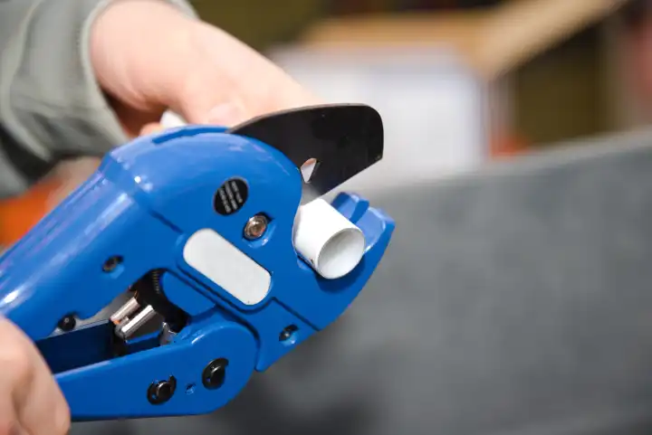 Tradesman plumber with single-stroke pipe cutter - close-up tool pipe cutter