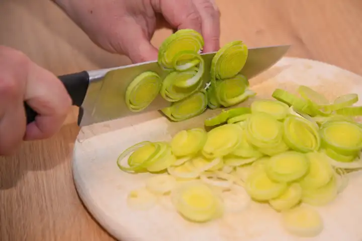 Person cutting leeks in the kitchen - leek freshly cut