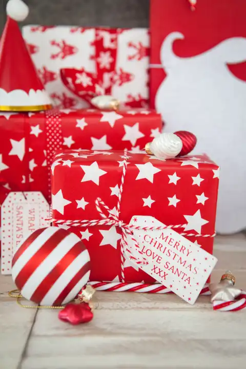 Rot weiss verpackte Geschenke zu Weihnachten auf Hintergrund aus Holz