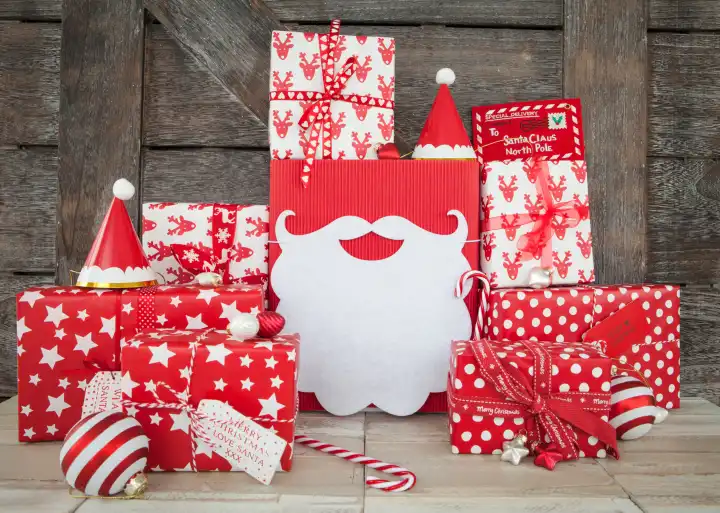 Rot weiss verpackte Geschenke zu Weihnachten auf Hintergrund aus Holz