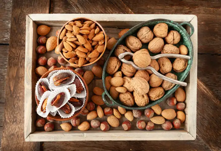 Verschiedene Nüsse und Datteln auf rustikalem Hintergrund aus Holz