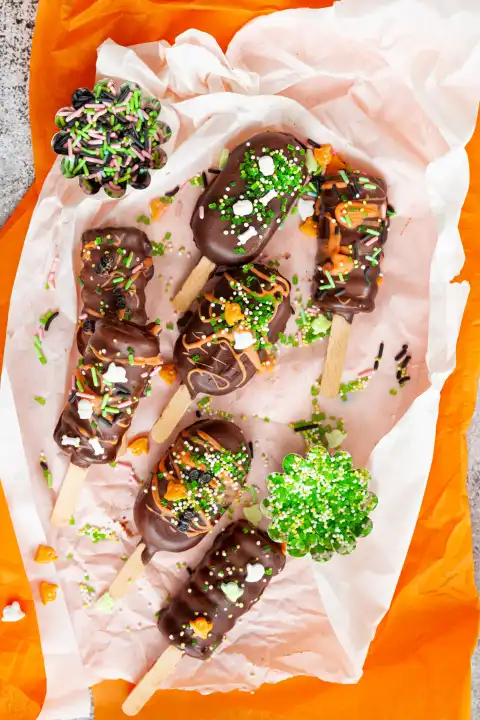 Kleine Kuchen am Stiel mit Schokoladenglasur und Zuckerstreusel zu Halloween
