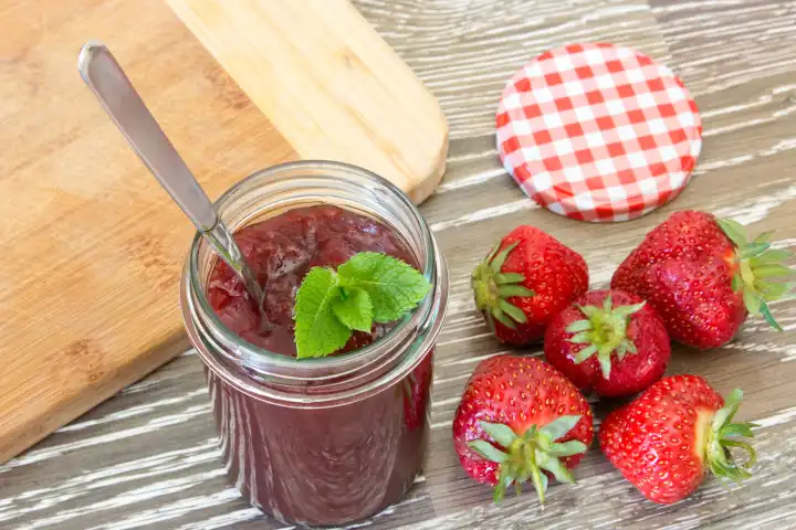 home made strawberry jam in a jar with mint leaves