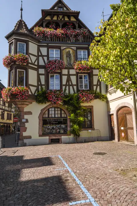 Blumengeschmückte Fassade eines Fachwerkhauses in der Altstadt von Kaysersberg, Elsass, Frankreich, beliebtes Touristenziel