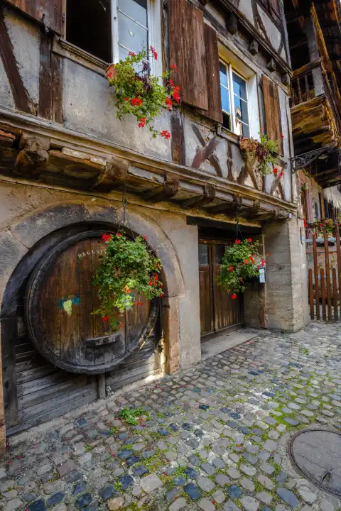 old timbered house in the village Bergheim, Alsace, Wine Route, France, wooden gate and wine barrel integrated in the house facade