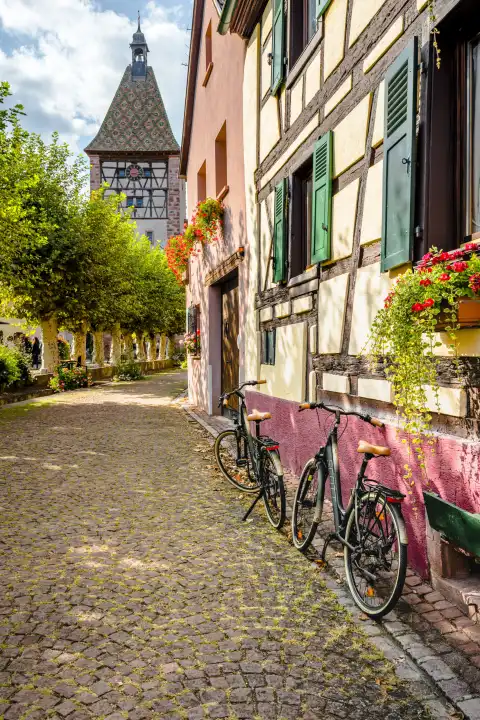 Alter Ortskern des Dorfes Bergheim mit Stadttor, Elsässer Weinstraße, Frankreich, Gasse mit Kopfsteinpflaster und Fahrrädern