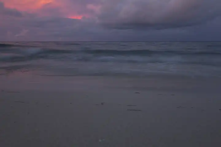 sandy beach at twilight, waves and clouds in the background