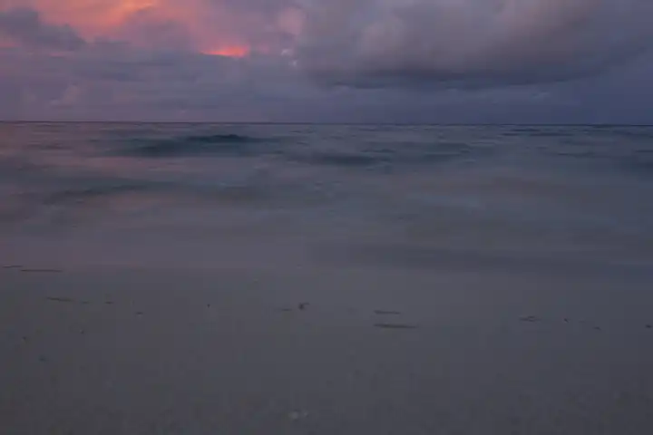 sandy beach at twilight, waves and clouds in the background. Selayar, south Sulawesi, Indonesia